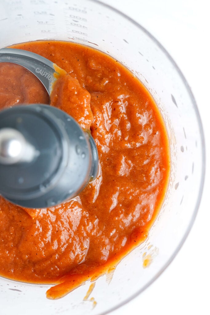 Tomates asados a la leña mezclados hasta que estén suaves para la salsa de enchiladas casera.
