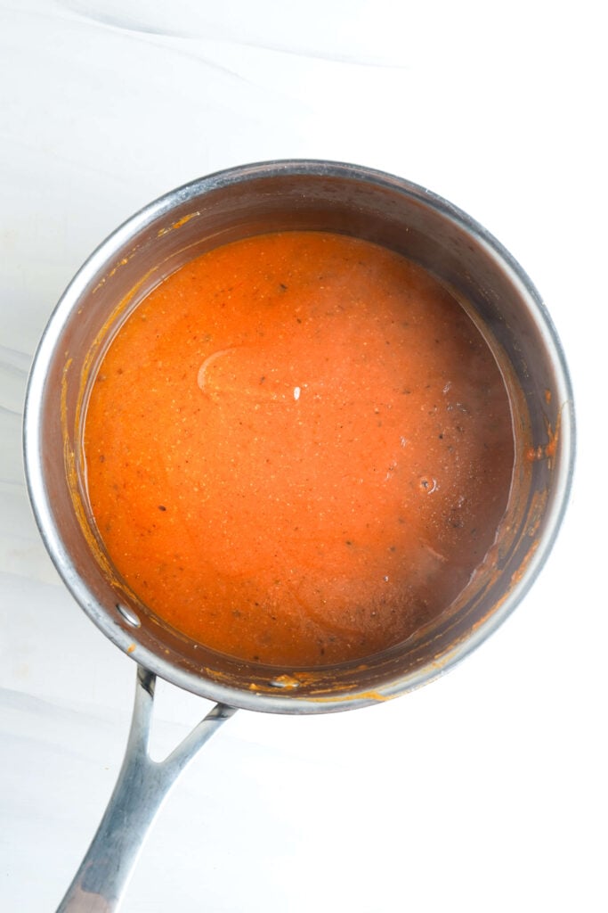 Salsa roja espesa de enchilada cocida a fuego lento y lista para usar en una cacerola.
