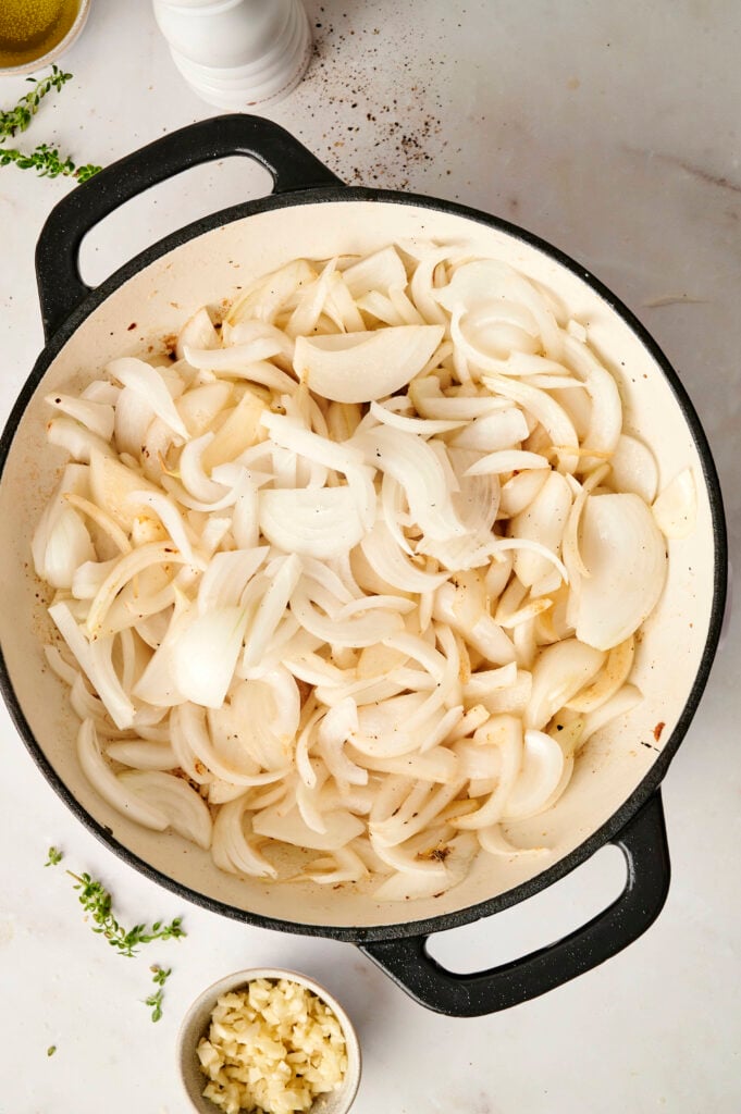 Cebollas en rodajas añadidas a una sartén, comenzando el proceso de caramelización.