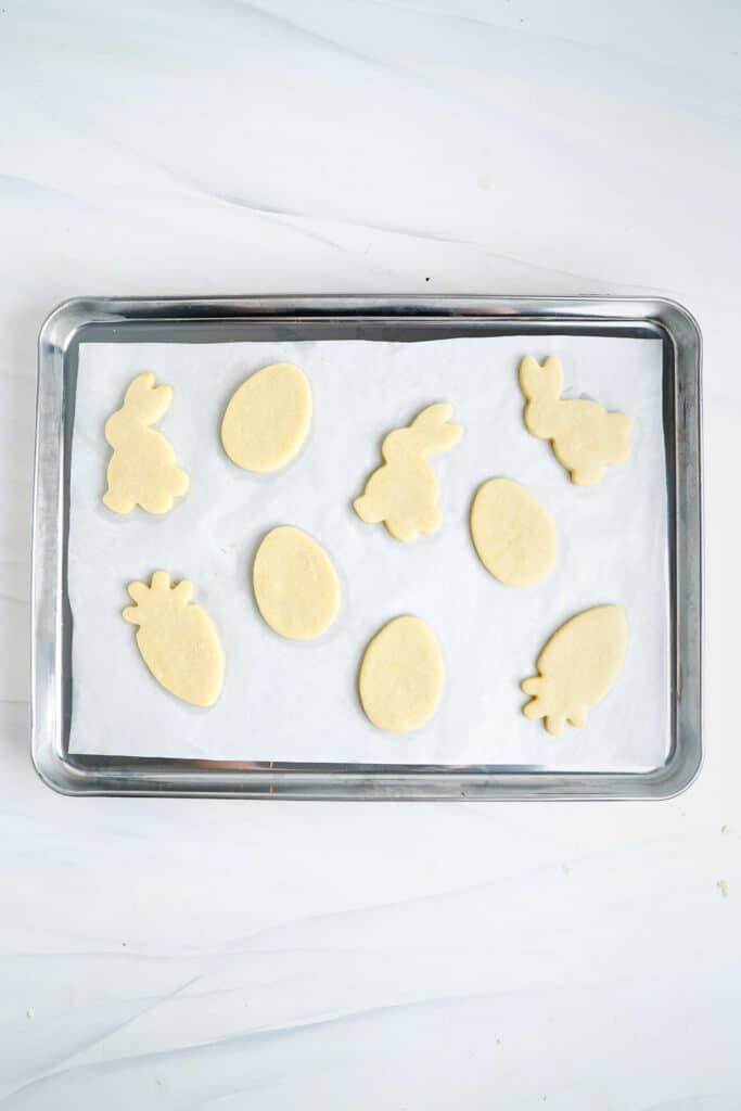 Galletas de azúcar de Pascua horneadas sobre una bandeja para hornear forrada con pergamino.