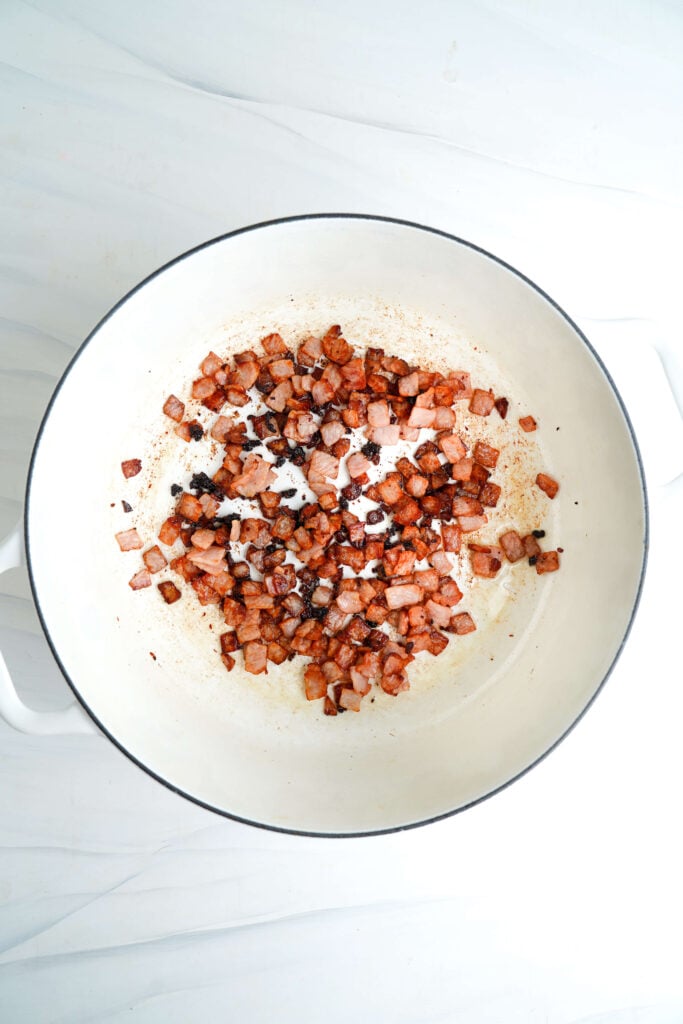 Bacon picado cocinándose en una olla de hierro fundido.