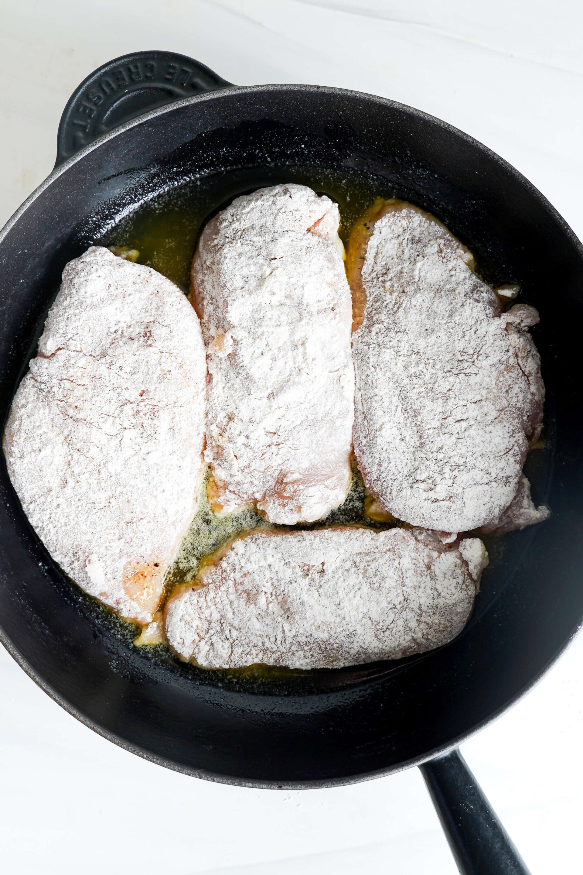 Pollo empanizado en harina listo para sellar en la sartén.
