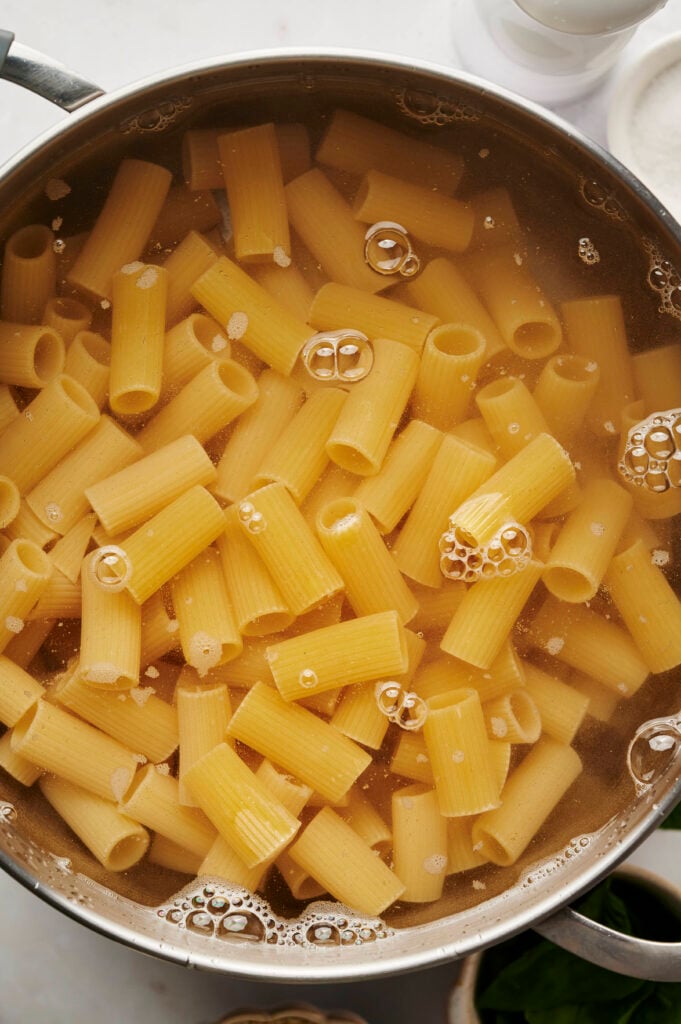 Pasta rigatoni cocinándose en una olla grande con agua hirviendo y salada