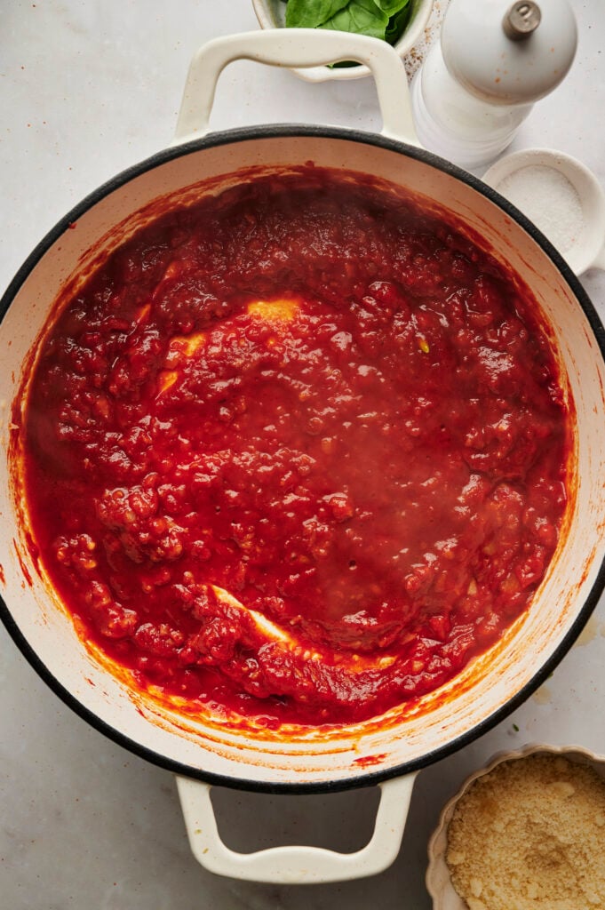 Salsa de pasta de tomate cocinando en una sartén blanca con el vodka recién añadido