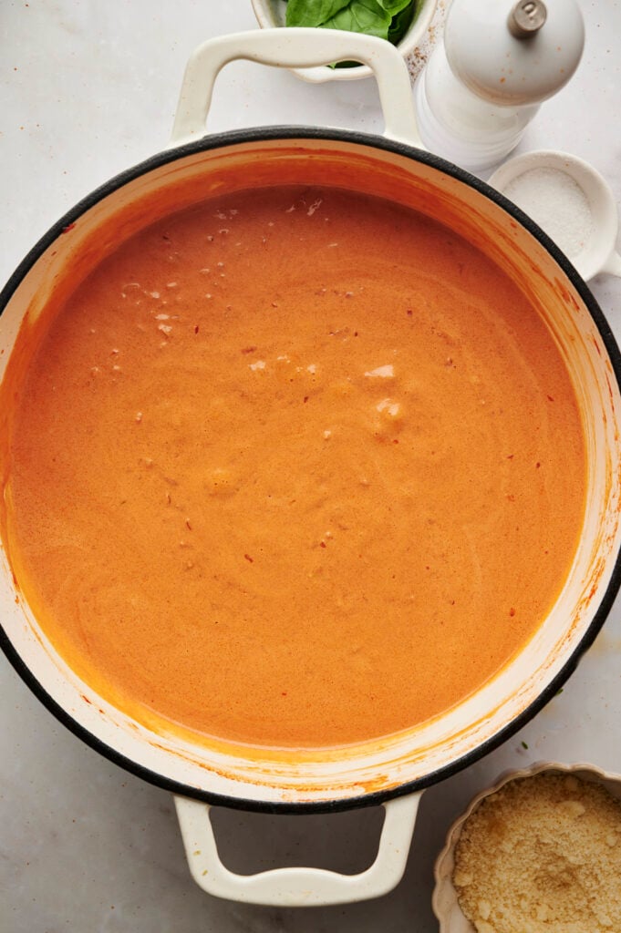 Salsa de vodka de color naranja suave y sedoso en una sartén blanca después de mezclarla con crema espesa