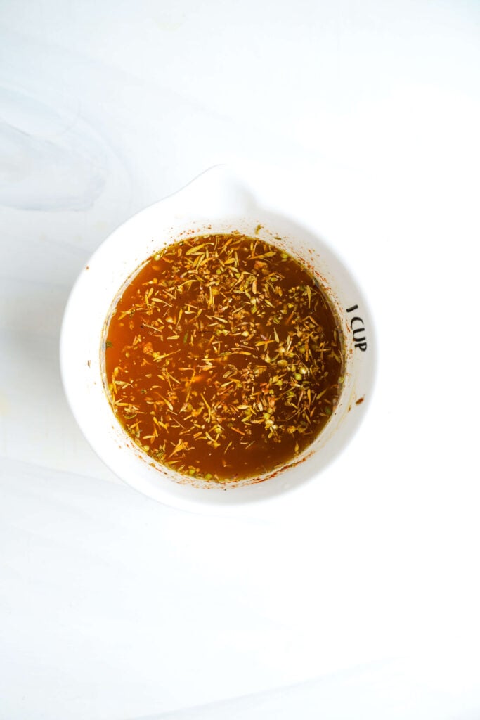 Marinada de limón y hierbas para pollo griego en una taza medidora blanca