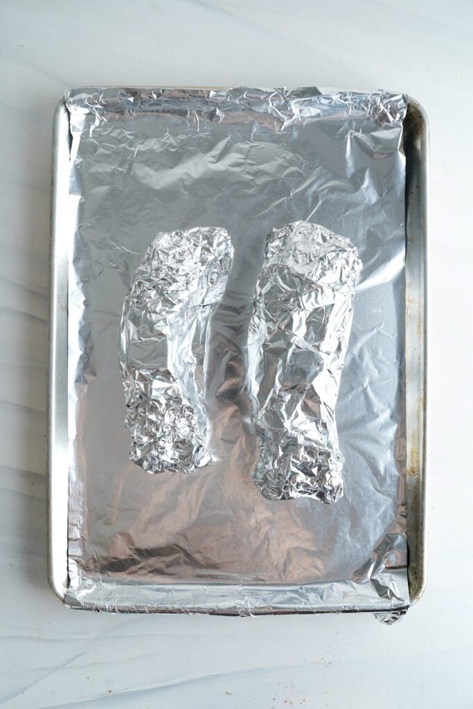 dos solomillos de cerdo envueltos en papel de aluminio sobre una bandeja | saborinspirado.com
