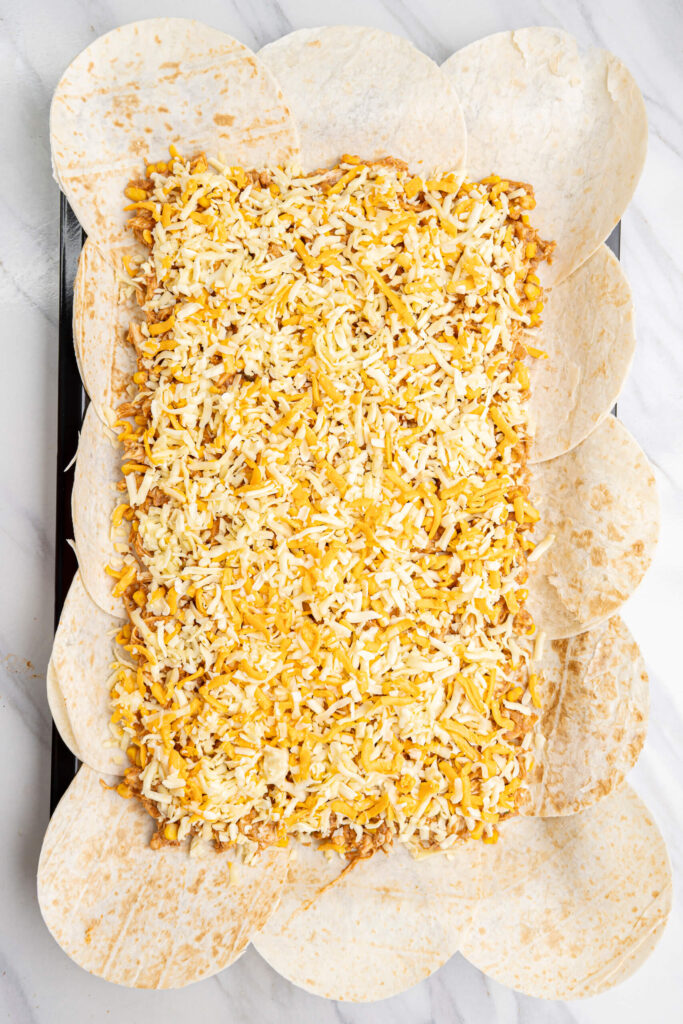 Capa de queso ensamblada sobre la mezcla de pollo y tortillas de harina
