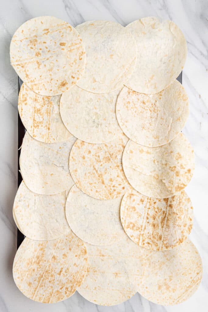 Tortillas de harina dispuestas en una bandeja, superpuestas para formar la base