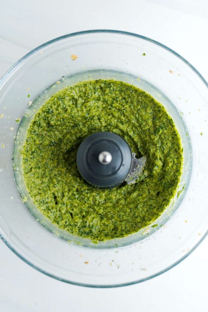 Pesto casero mezclado en un procesador de alimentos después de añadir aceite de oliva.